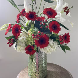 Red gerbera daisies and white lilies in a glittery vase