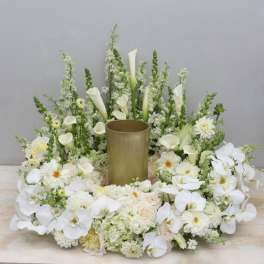 White floral arrangement with orchids, calla lilies, and roses around a gold vase