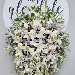 Large white and lavender funeral spray on an easel