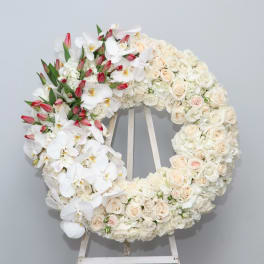 Large white floral wreath with pale roses and orchids on an easel