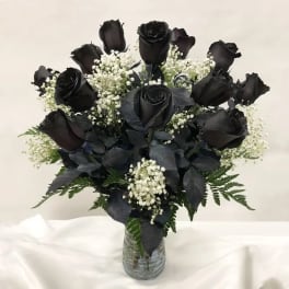 Bouquet of black roses with white baby's breath in a clear glass vase