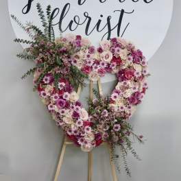 Heart-shaped floral wreath on an easel with pink and white roses