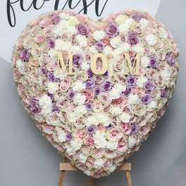 Heart-shaped floral wall with pastel roses and white blooms spelling MOM