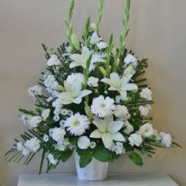 White lilies and daisies arranged in a white vase