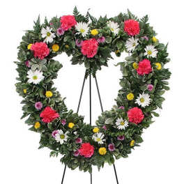 Heart-shaped floral wreath on a stand with pink, white, and yellow flowers