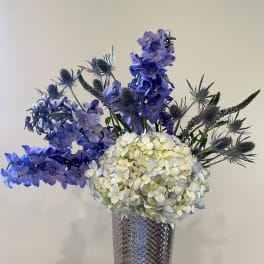Blue and white floral arrangement in a tall textured vase
