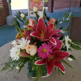 Bouquet of pink lilies, white daisies, and roses in a glass vase