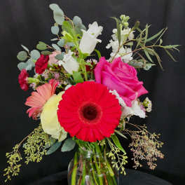Mixed bouquet in a glass vase with pink, red, white, and peach flowers