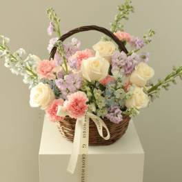 Basket of cream roses and pastel flowers with a ribbon