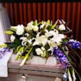 White floral arrangement with purple accents on a casket