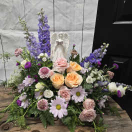Mixed pastel floral arrangement with an angel figurine centerpiece