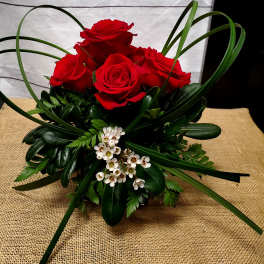 Red roses arranged with dark greenery and small white blossoms