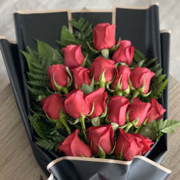 Bouquet of red roses wrapped in black paper with a red ribbon
