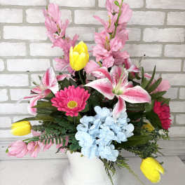 Colorful floral arrangement in a white vase with pink, yellow, blue, and white blooms
