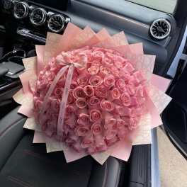 Large bouquet of pink roses wrapped in pink paper with a ribbon