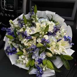 Bouquet of white lilies, blue flowers, and pale hydrangeas