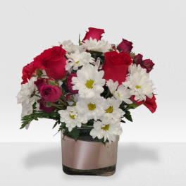 Compact red rose and white daisy bouquet arranged in a square glass vase