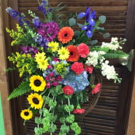 Large colorful flower arrangement on a stand with sunflowers, gerberas, and irises
