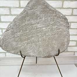 Engraved memorial stone on a metal stand with Bible verse text