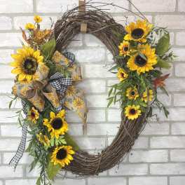 Sunflower wreath with ribbon on a white brick wall