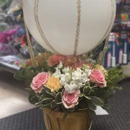 Basket arrangement with pink roses and white flowers beneath a large white balloon