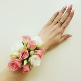 Pink and white rose wrist corsage on a hand