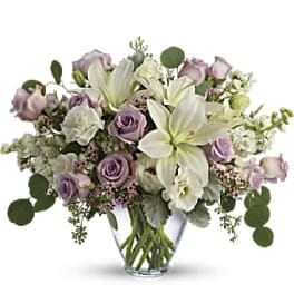 Lavender roses and white lilies in a clear glass vase