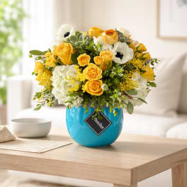 Yellow and white flower arrangement in a blue vase