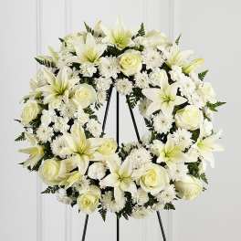 Standing wreath of white lilies, roses, and mums on a metal easel stand