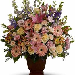 Large pastel arrangement of pink lilies, gerbera daisies, and cream roses in a brown pedestal vase