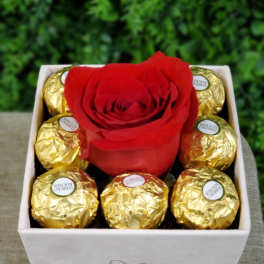 Square box with a single red rose surrounded by gold-wrapped chocolates