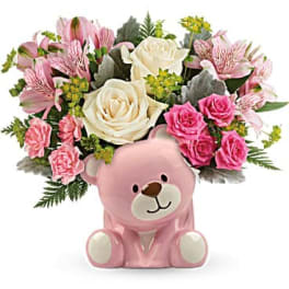 Pink teddy bear with a bouquet of pink and white flowers