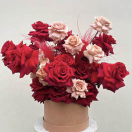 Bouquet of red and blush roses in a round hatbox