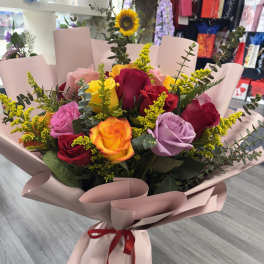 Bouquet of multicolored roses wrapped in pale pink paper