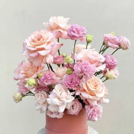 Pink and peach roses with carnations in a round box