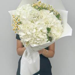 Large white bouquet with small yellow daisies wrapped in white paper