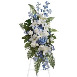 Tall white and blue floral spray with lilies and roses on a clear stand