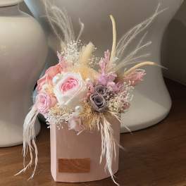 Pink and white rose arrangement in a blush box with dried feathers