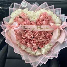 Heart-shaped bouquet of pink and white roses with ribbon bows
