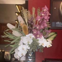 Tall floral arrangement with white and pink orchids in a vase