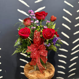 Bouquet of red roses with a glittery red bow in a glass vase