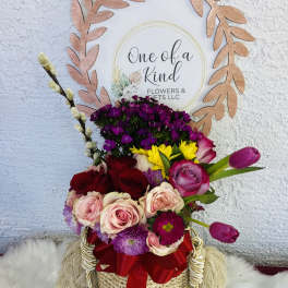 Mixed bouquet in a woven basket with a red ribbon