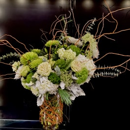 Tall floral arrangement with white and green blooms in a glass vase