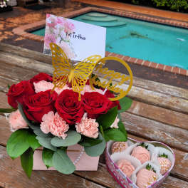 Red roses and pink carnations in a gift box with a birthday topper
