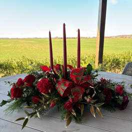 Red floral centerpiece with three tall candles on a table