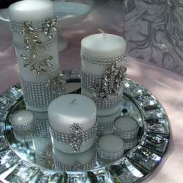 White candles decorated with rhinestones on a mirrored tray