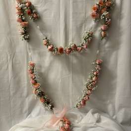Pink rose garland arranged in a heart shape with a ribbon bow