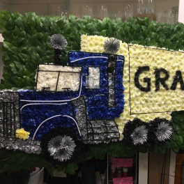 Floral truck display with a large yellow sign reading GRAMPS