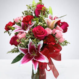 Bouquet of pink and red roses with lilies in a glass vase