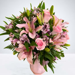 Pink lilies and roses arranged in a pink vase